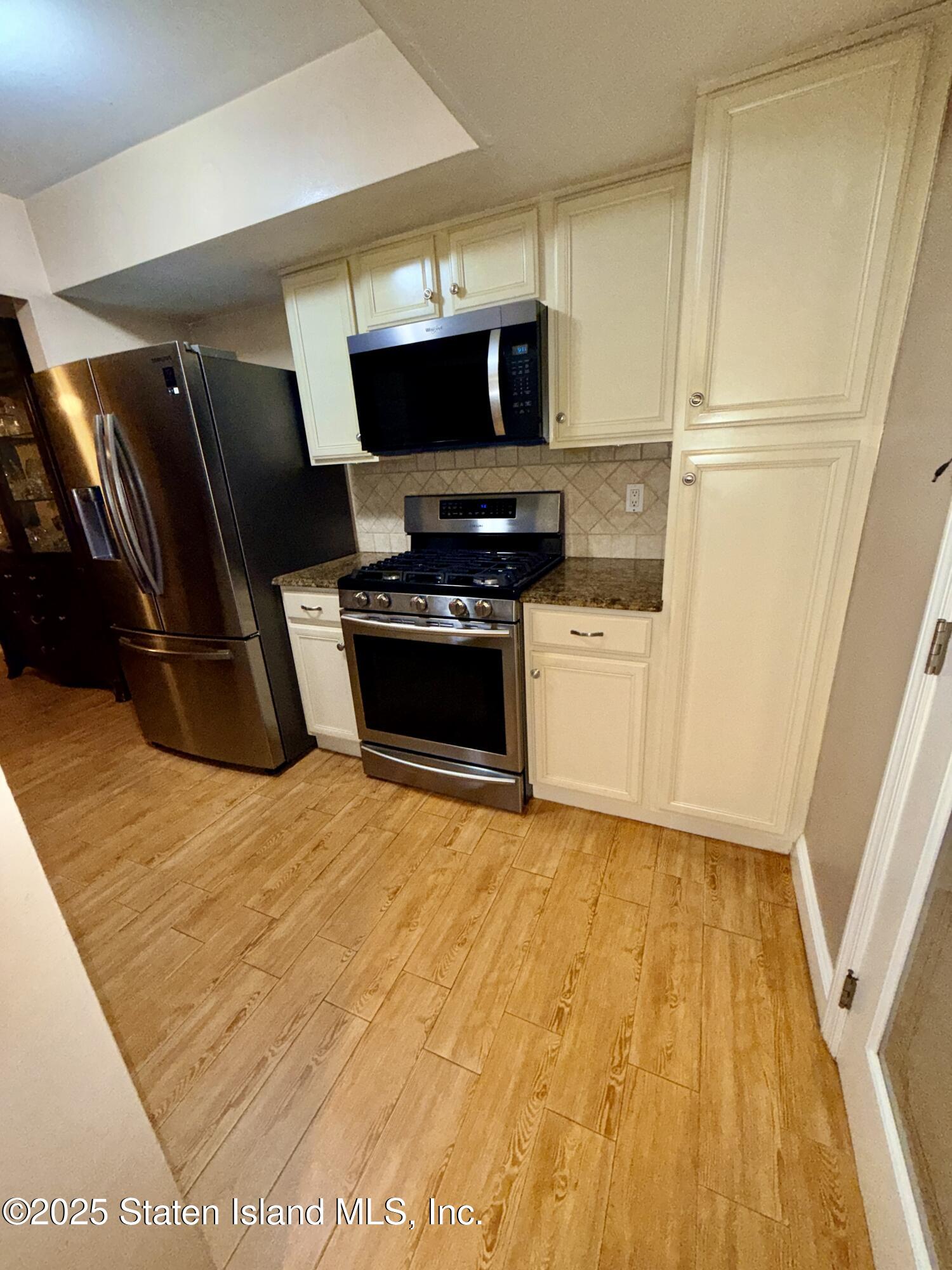 1446 Forest Hill Road, Unit 4 Staten Island, NY 10314 - Photo 9 of 24 a kitchen with granite countertop a refrigerator and a stove top oven