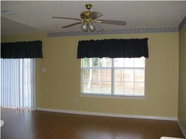 a view of a room with wooden floor and a chandelier fan