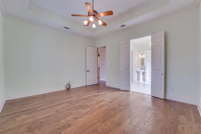 an empty room with wooden floor and a ceiling fan