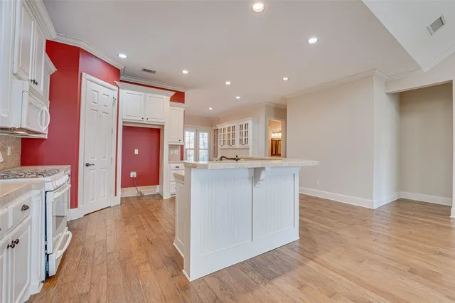 a kitchen with kitchen island granite countertop a stove top oven a sink and a refrigerator