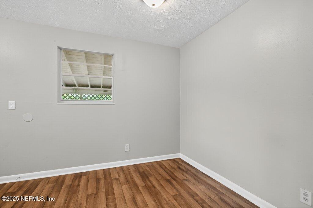 7326 Melvin Road Jacksonville, FL 32210 - Photo 12 of 42 a view of an empty room with wooden floor and a window