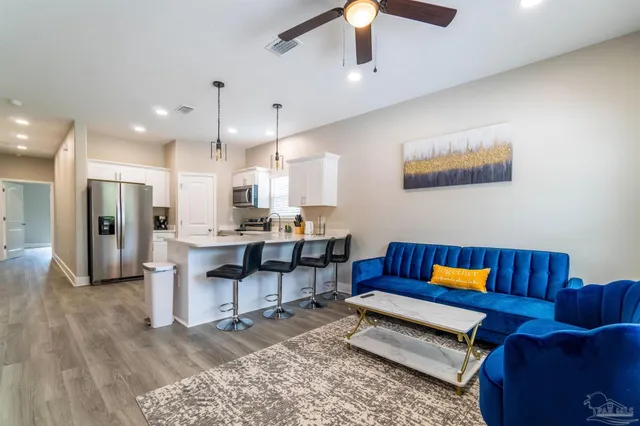 a living room with furniture kitchen view and a chandelier