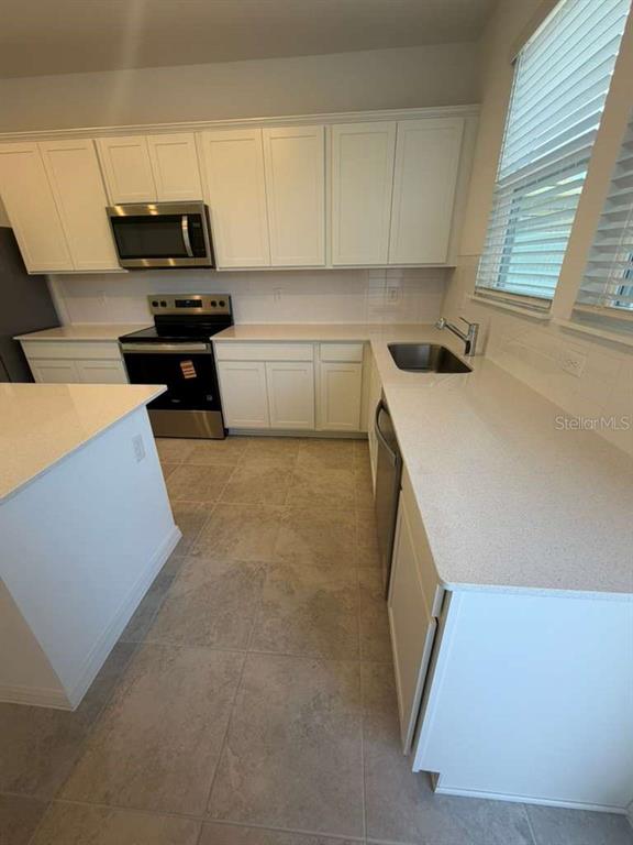4617 Orchard View Alley Winter Garden, FL 34787 - Photo 9 of 32 a kitchen with a sink a stove and white cabinets