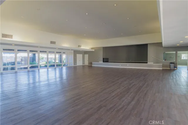 a view of an empty room with wooden floor and a kitchen