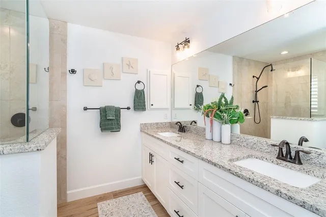 a bathroom with a granite countertop sink a mirror and shower