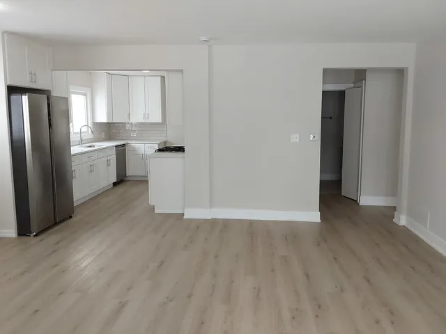 a view of a kitchen with a sink and dishwasher a refrigerator with wooden floor