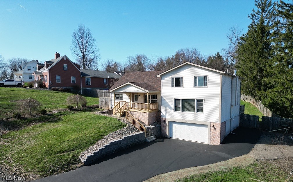 View of front of home with a garage, driveway, a wooden deck, and brick siding