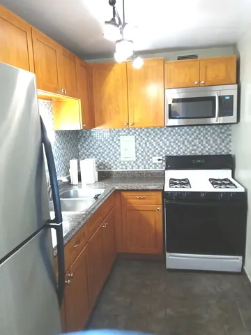 a kitchen with stainless steel appliances granite countertop a sink and a refrigerator