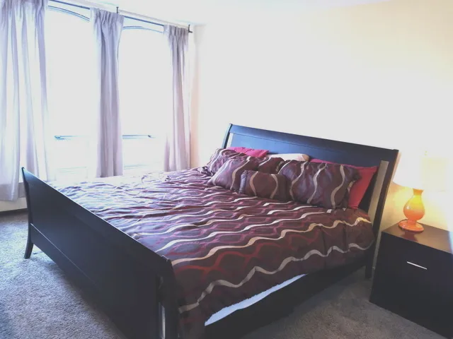 a bed sitting in a bedroom next to a window and dresser