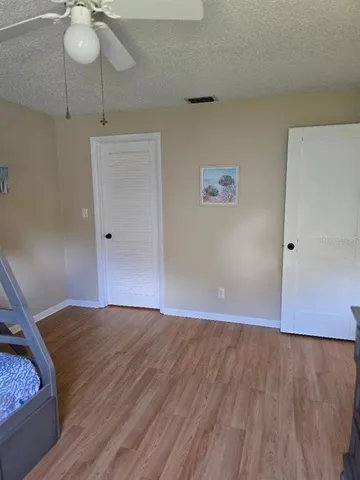 a view of an empty room with wooden floor and a chandelier