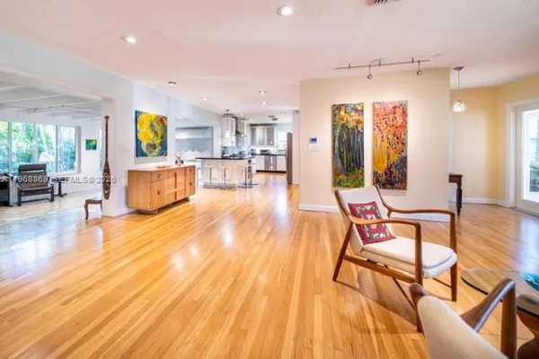 a kitchen with stainless steel appliances granite countertop a stove top oven a sink a dining table and chairs with wooden floor