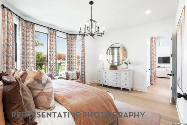 a spacious bedroom with a bed a dresser and large windows
