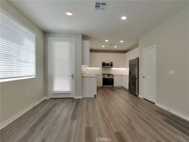 a view of kitchen with stainless steel appliances granite countertop a stove top oven a sink dishwasher and a refrigerator with wooden floor