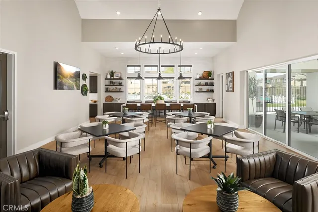 a living room with couches a fireplace and kitchen view with wooden floor