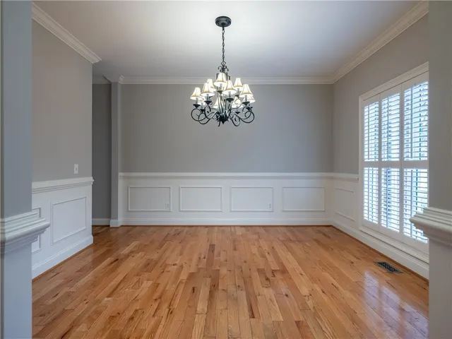 a view of an empty room with wooden floor and windows