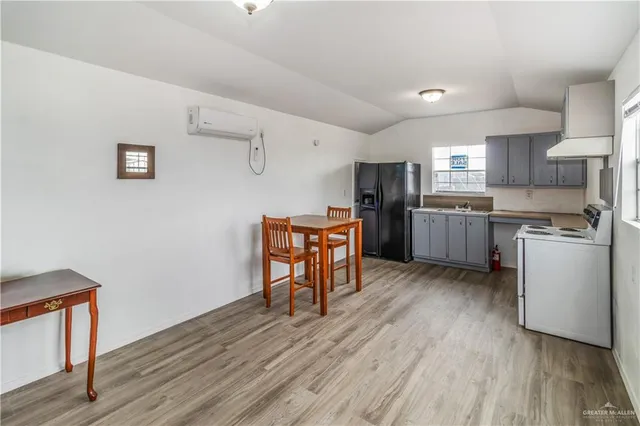 a large white kitchen with granite countertop a stove a sink a dining table and chairs with wooden floor