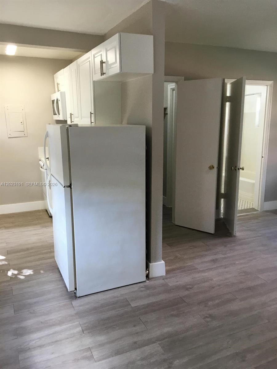 520 Southwest 4th Street, Unit 5 Miami, FL 33130 - Photo 11 of 11 an empty room with wooden floor and a refrigerator