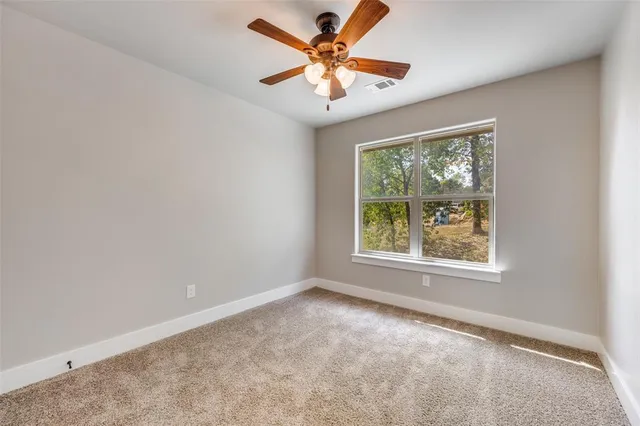 an empty room with a window and a fan