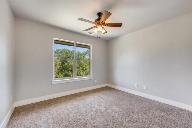 an empty room with windows and ceiling fan
