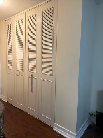 an empty room with wooden floor and closet area