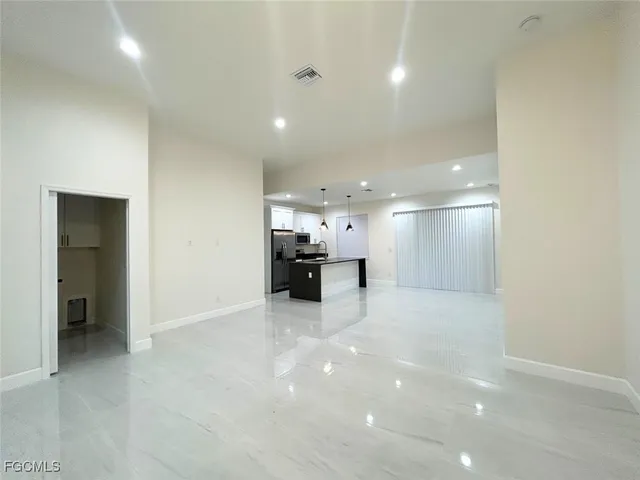 an empty room with kitchen view and a window