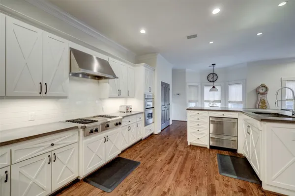 a large kitchen with cabinets wooden floor and stainless steel appliances