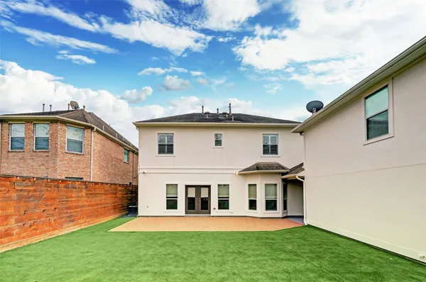 a view of a white house with a big yard and potted plants