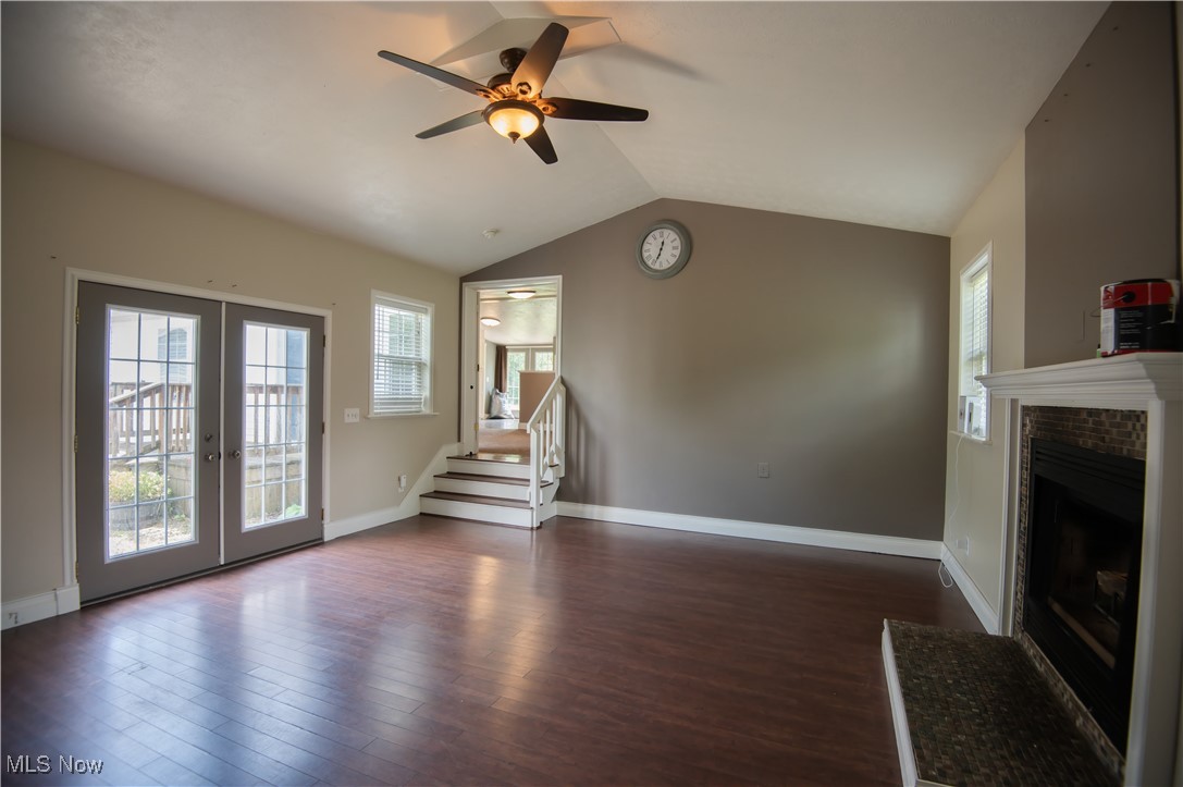 4594 Center Road Andover, OH 44003 - Photo 14 of 39 Unfurnished living room with stairs, vaulted ceiling, dark wood-type flooring, ceiling fan, and a brick fireplace