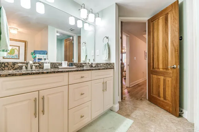 a en suite bathroom with a granite countertop sink and a mirror