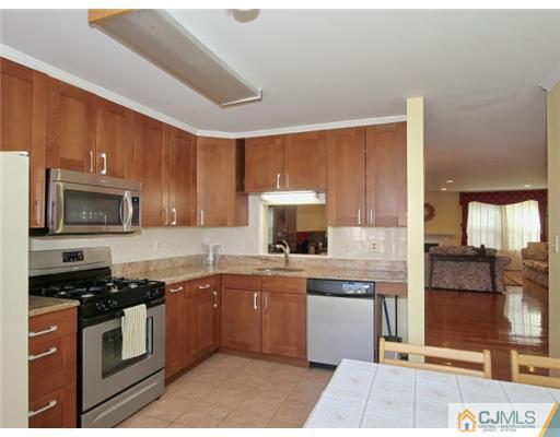4504 Stonehedge Road Edison, NJ 08820 - Photo 7 of 16 a kitchen with stainless steel appliances granite countertop a stove top oven a sink dishwasher a refrigerator and cabinets with wooden floor