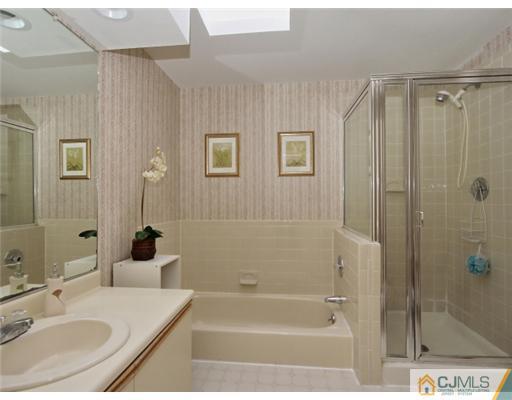 4504 Stonehedge Road Edison, NJ 08820 - Photo 9 of 16 a bathroom with a granite countertop sink a mirror a bathtub and shower