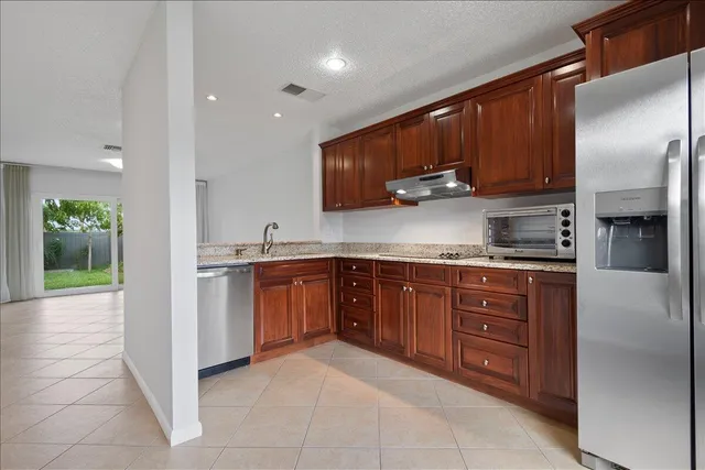 a kitchen with stainless steel appliances granite countertop a refrigerator and a stove top oven