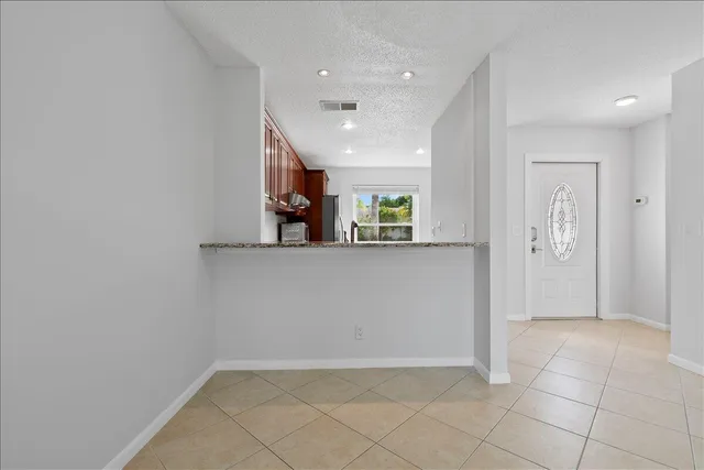 an empty room with kitchen view and windows