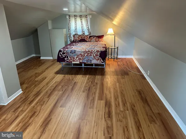 a spacious bedroom with a bed and wooden floor