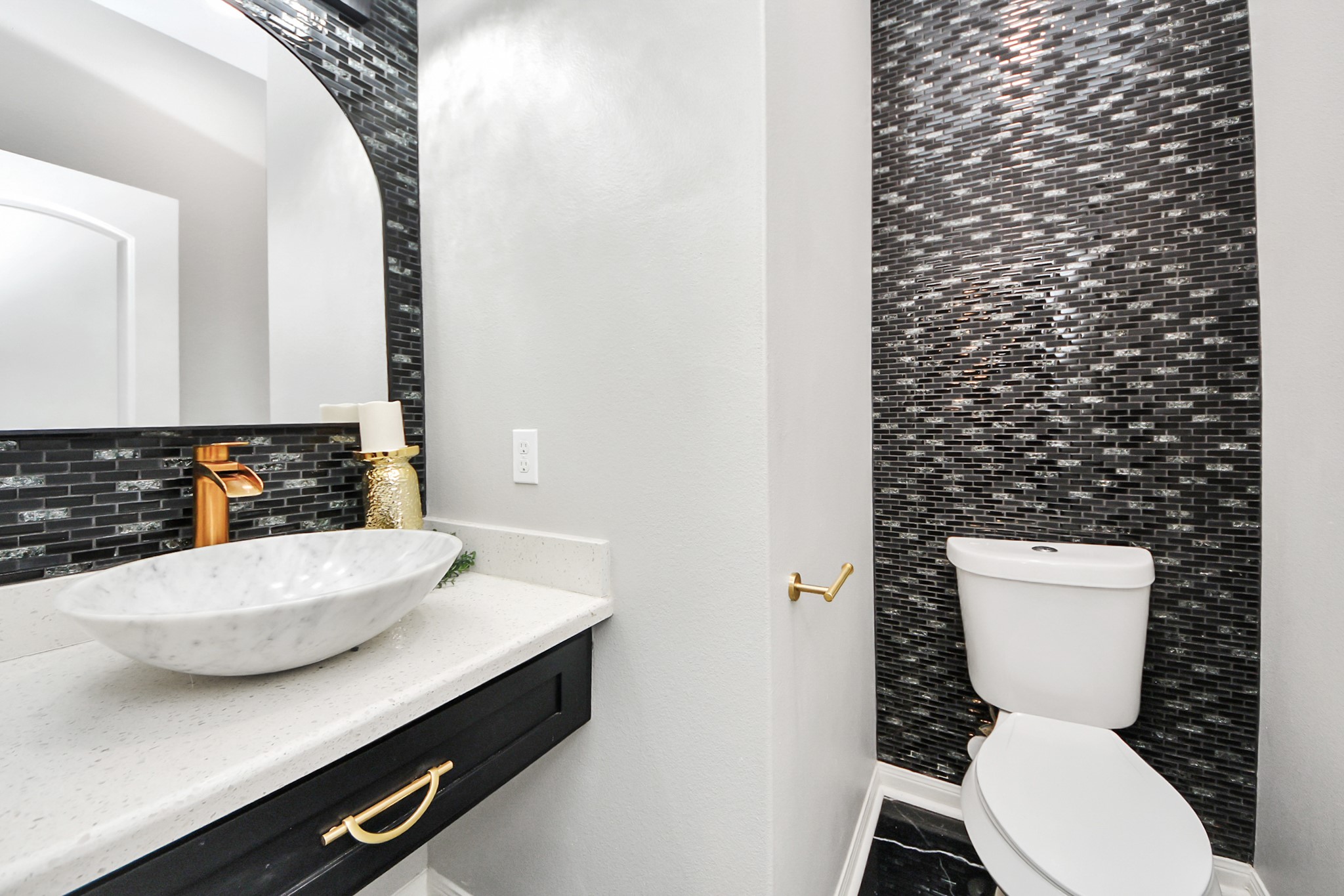 6931 Primrose Road Baytown, TX 77521 - Photo 12 of 50 Elegant half bath with vessel sink, gold fixtures, and modern tile accent wall.