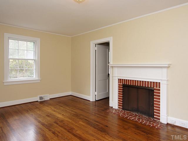 3014 Mayview Road Raleigh, NC 27607 - Photo 3 of 21 an empty room with wooden floor a fireplace and windows