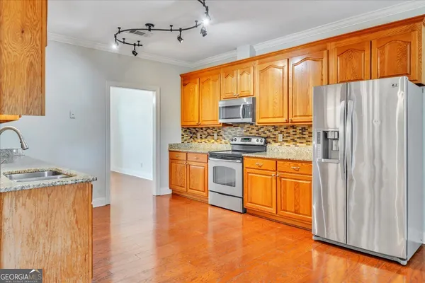 a kitchen with stainless steel appliances granite countertop a refrigerator a sink dishwasher and wooden cabinets with wooden floor