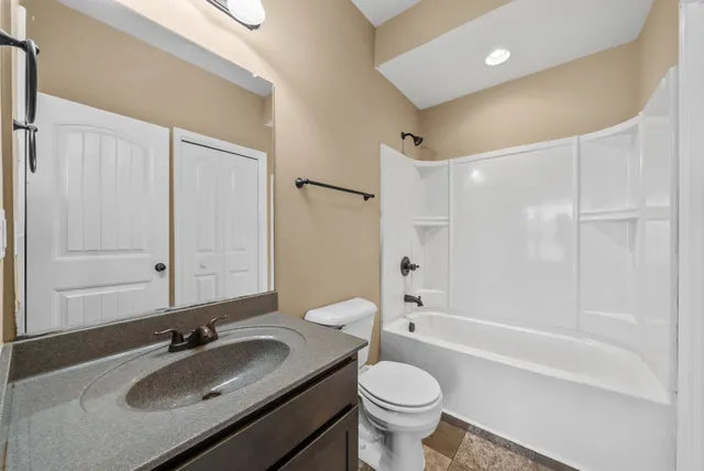a bathroom with a granite countertop sink toilet and shower