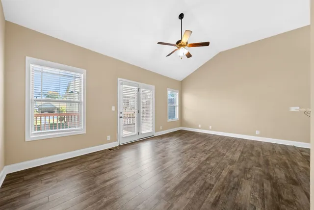 a view of an empty room with a window and wooden floor