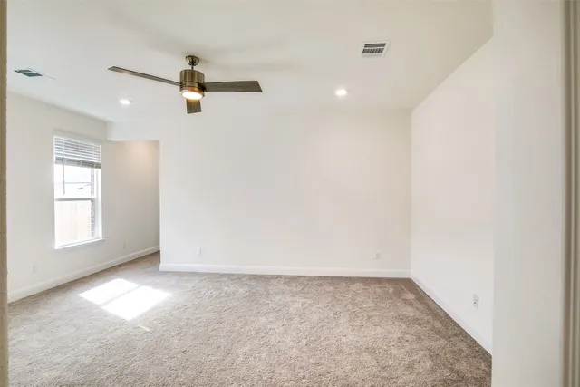 an empty room with windows and ceiling fan