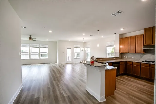 a kitchen with stainless steel appliances granite countertop wooden floors and view living room