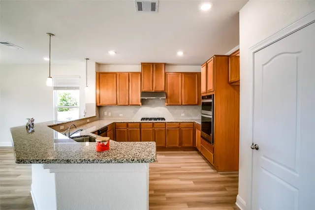 a kitchen with granite countertop a sink a counter top space stainless steel appliances and cabinets