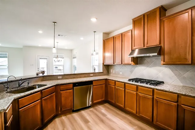 a kitchen with stainless steel appliances granite countertop wooden cabinets a sink and a granite counter tops