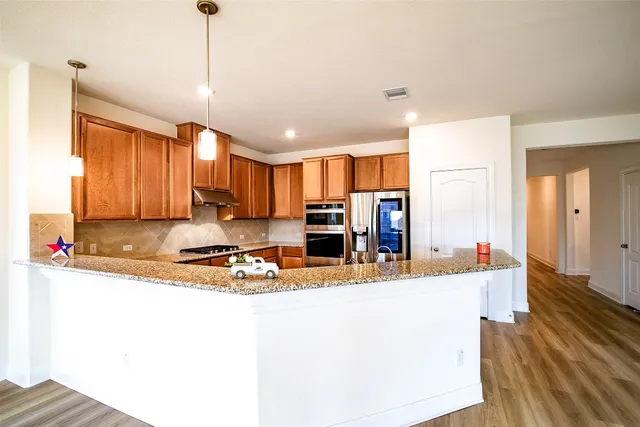 a view of a kitchen with kitchen island a large counter top space stainless steel appliances and cabinets