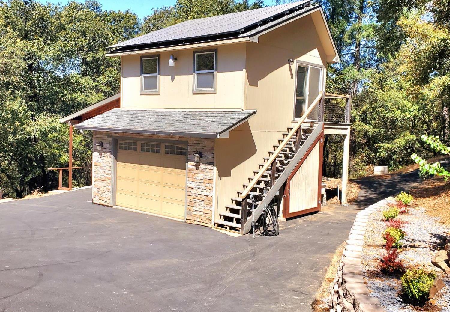 1440 Dog Bar Road Colfax, CA 95713 - Photo 75 of 93 View of front facade of Guest House (ADU)) with stairway, stone siding, a garage/shop, roof mounted solar panels, 4.7KW system and driveway.