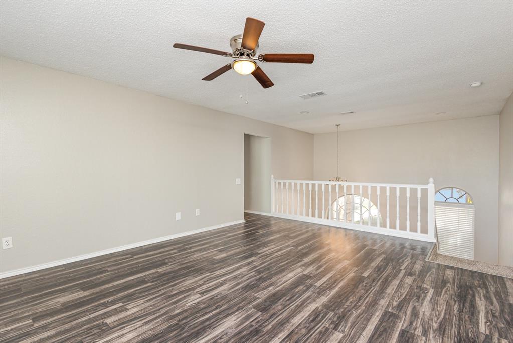 7100 Layla Road Arlington, TX 76016 - Photo 10 of 19 Empty room featuring dark wood-style flooring, ceiling fan, a textured ceiling, and a chandelier