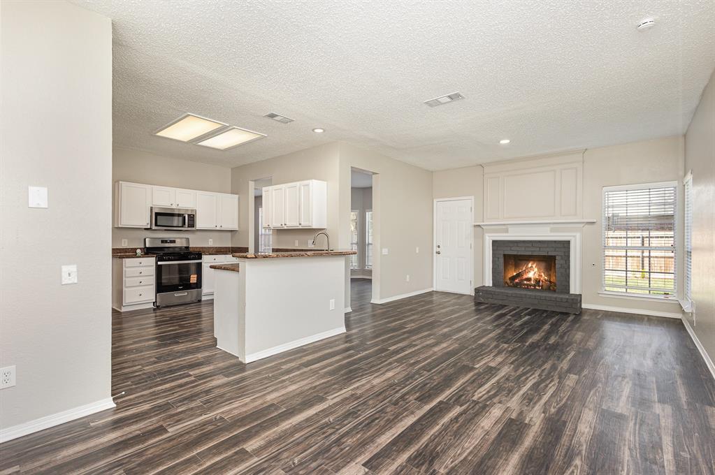 7100 Layla Road Arlington, TX 76016 - Photo 19 of 19 Kitchen featuring open floor plan, stainless steel appliances, a textured ceiling, dark wood-style floors, and dark countertops