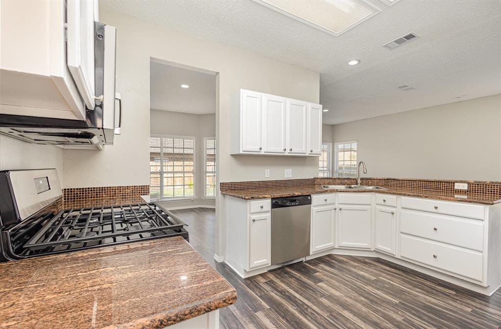 7100 Layla Road Arlington, TX 76016 - Photo 6 of 19 Kitchen with plenty of natural light, a textured ceiling, recessed lighting, dark wood-type flooring, and a peninsula