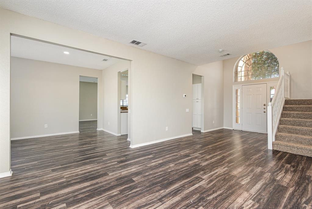 7100 Layla Road Arlington, TX 76016 - Photo 8 of 19 Unfurnished living room with a textured ceiling, stairway, and dark wood-style floors