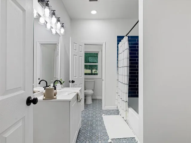 a view of a hallway with wooden floor and a bathroom